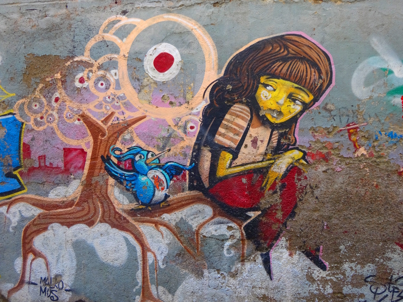 Street art in Granada of a sad girl sitting in a tree